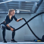 A Woman training her core using battle ropes.